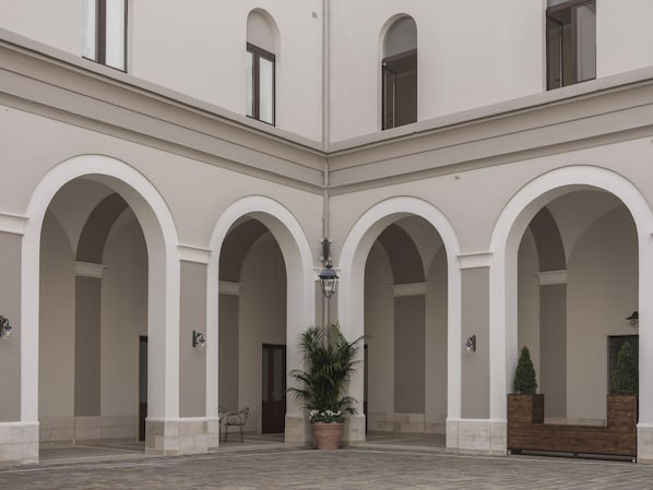 Un patio con arcos, una planta en maceta y un banco.