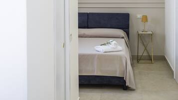 Un dormitori amb un llit, una taula de nit amb una làmpada i un objecte decoratiu a la paret.