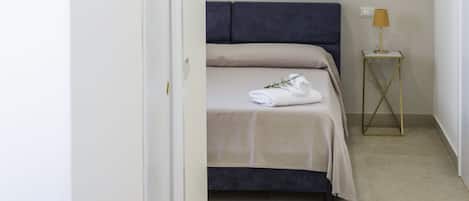 Un dormitorio con una cama, una mesita de noche con lámpara y un adorno de pared.