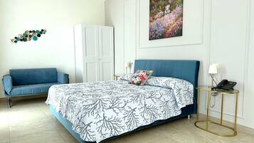 Een slaapkamer met een bed, een blauwe bank, een kledingkast, een schilderij en een telefoon op een nachtkastje.