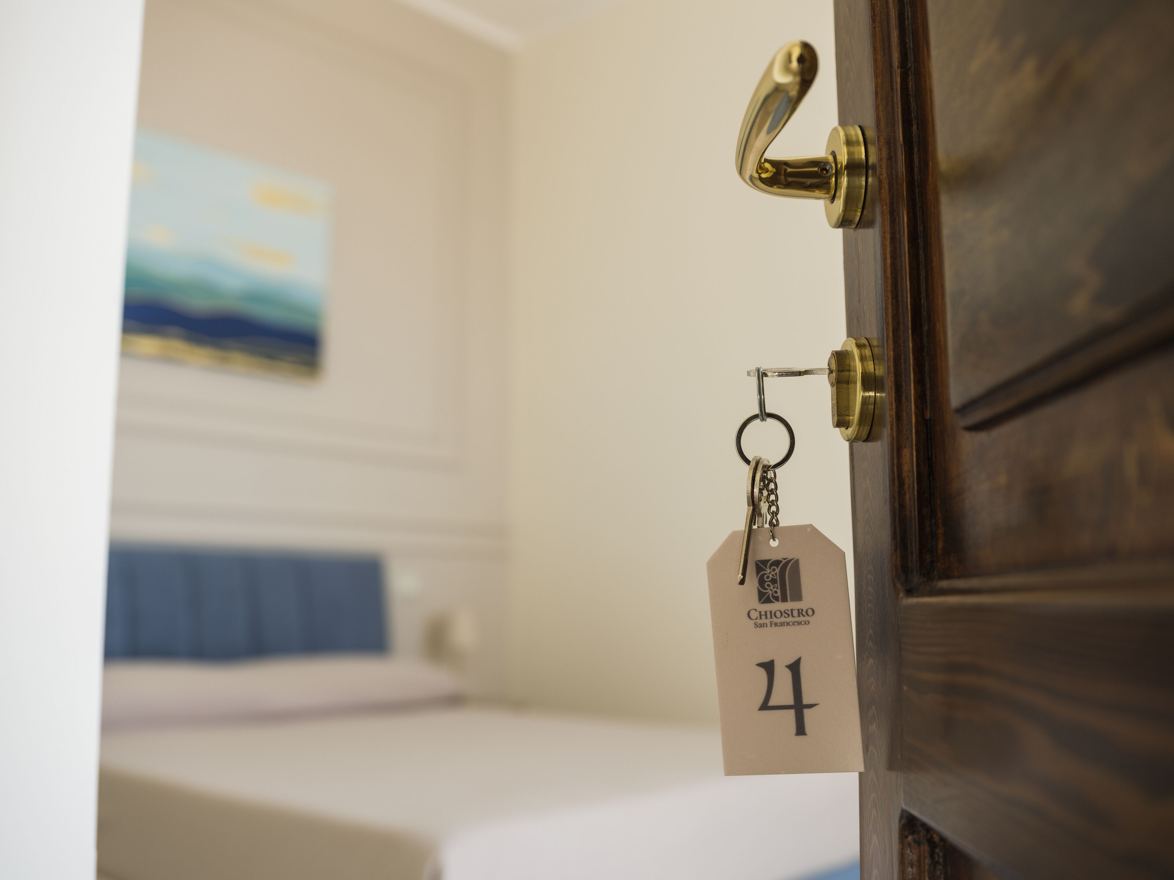 Een hotelkamerdeur met een sleutelkarthouder waarop een kamer nummer en een tag met de hotelnaam staan.