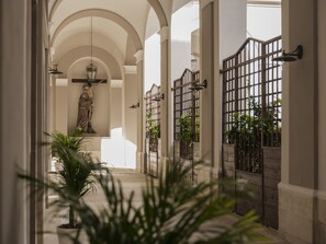 A corridor with arches, a statue, and potted plants. - Residenza d'epoca Chiostro San Francesco (Naples)