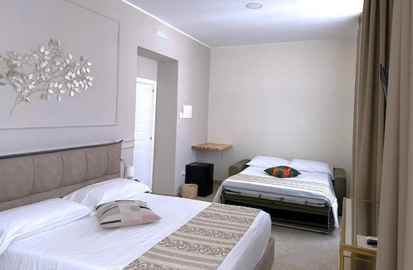 A hotel room with two beds, a decorative wall piece, a small shelf, and a bedside table. - Residenza d'epoca Chiostro San Francesco (Naples)