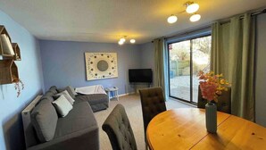 A living room with a sofa, a dining table, and a TV.
