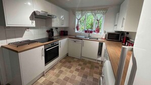 A compact kitchen with white cabinets, a microwave, a stove, and a dishwasher.