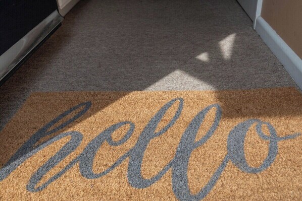 Eine Fußmatte mit dem Wort 'hello' in blauer Schrift auf beigem Untergrund.