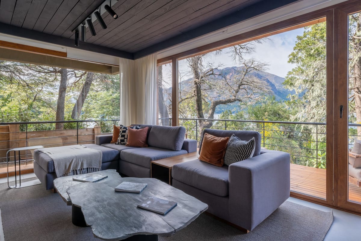 A modern living room with a large sliding glass door leading to a balcony with a mountain view.