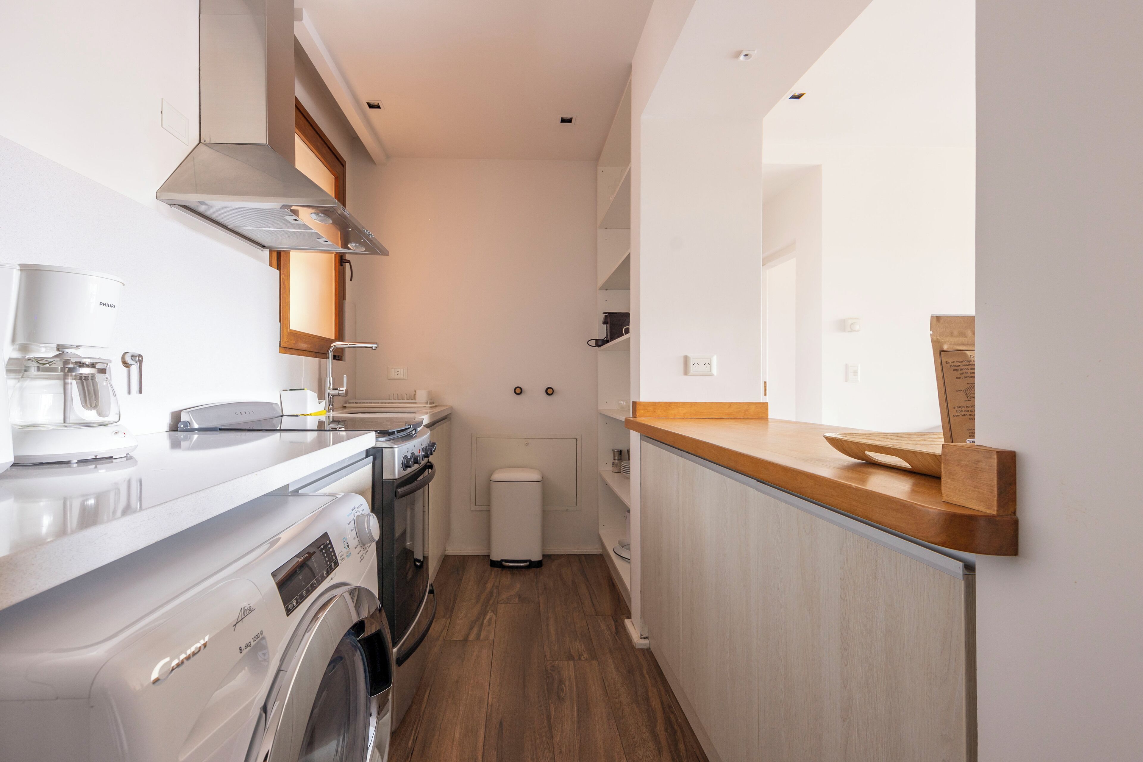 Cocina compacta con lavadora, cafetera y horno integrado.