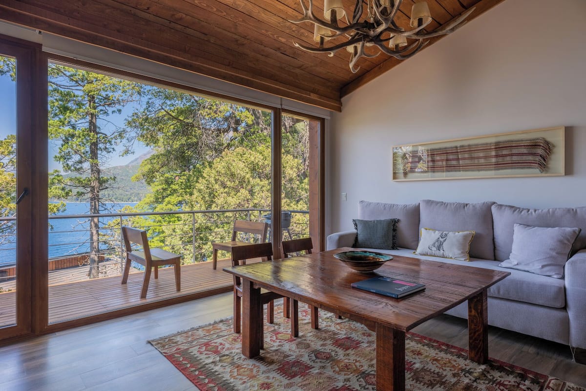 A spacious living area with a wooden coffee table, a sofa, and a view of the sea through large sliding glass doors.