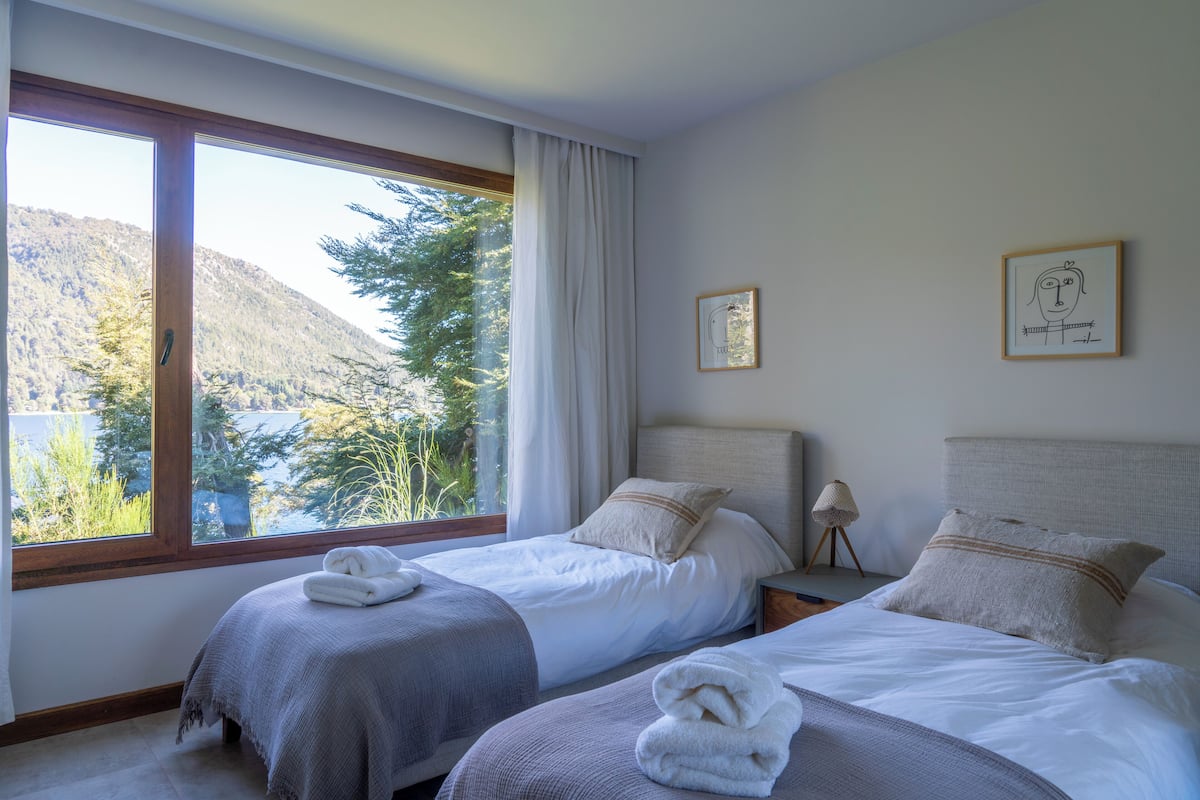 A bedroom with two beds, a large window, and a view of a mountain.