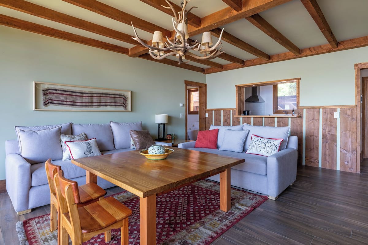 A spacious living room with a wooden dining table, two sofas, and a chandelier.