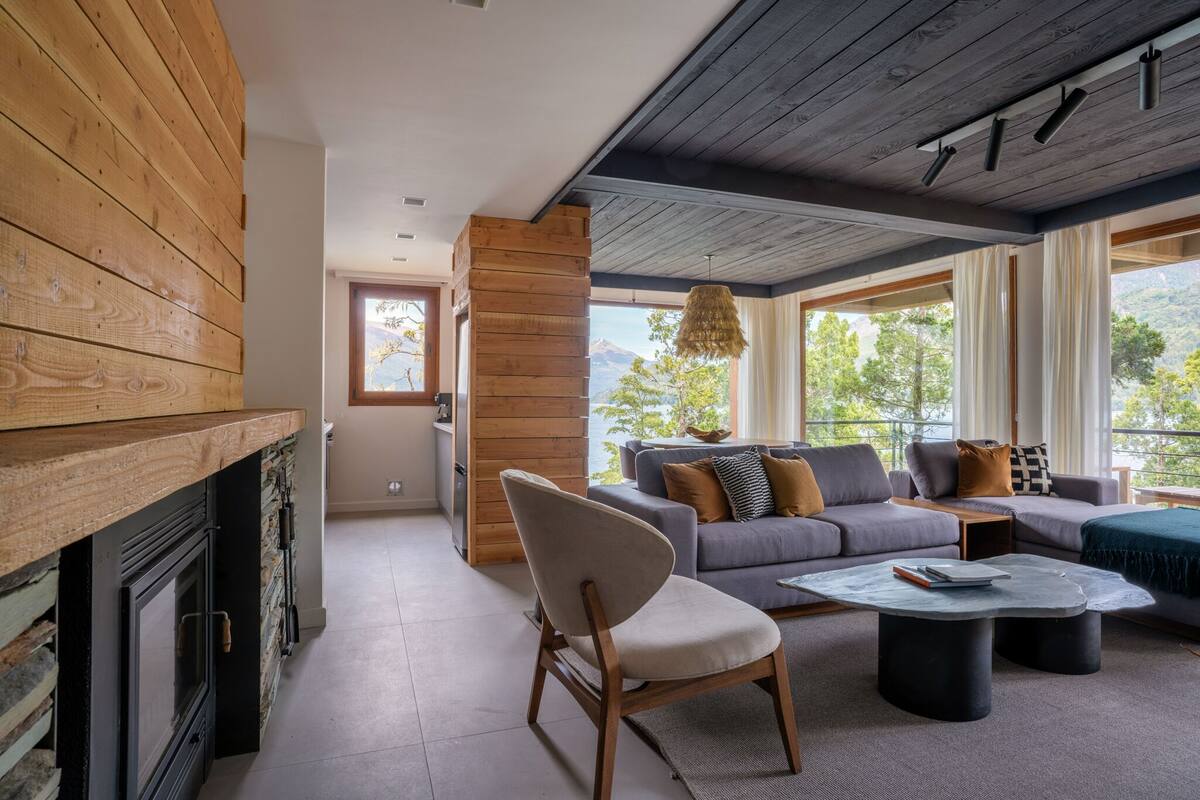 A modern living room with a fireplace, a sofa set, and a dining area.