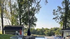 A pool area with a concrete pathway, seating, and a covered patio. - Seasonal Heated pool in the Bluegrass (Union)