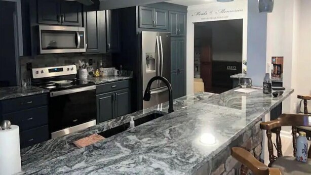 A modern kitchen with dark cabinets, stainless steel appliances, and a marble countertop. - Seasonal Heated pool in the Bluegrass (Union)