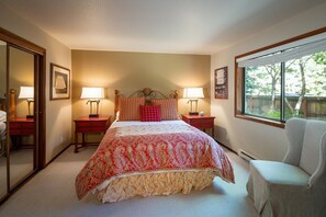 Une chambre à coucher avec un grand lit, deux tables de chevet, une chaise, une fenêtre et un miroir.