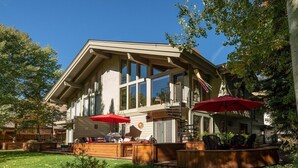 Un edificio moderno de dos pisos con un amplio espacio de terraza, mobiliario exterior y una escalera que conduce a un nivel superior.