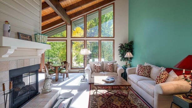 Amplia sala de estar con chimenea, ventanas grandes, comedor y una zona de estar acogedora.