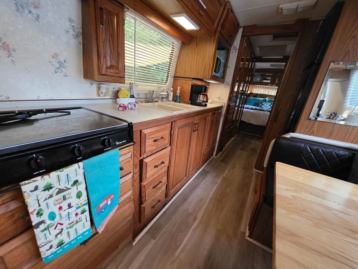 A compact kitchen with wooden cabinets, a microwave, and a stove.