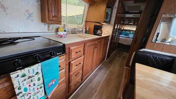 A compact kitchen with wooden cabinets, a microwave, and a stove.