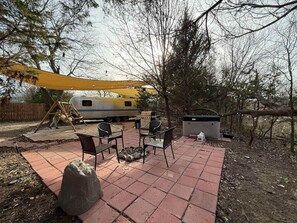 Une terrasse avec des meubles d’extérieur, une balançoire et un espace barbecue.