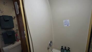 Een kleine badkamer met een douche, toilet en een plank met toiletartikelen.