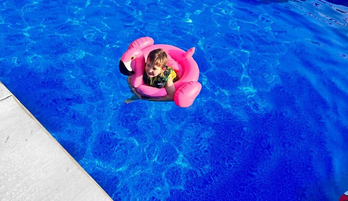 A child in a pink inflatable pool float in a swimming pool.