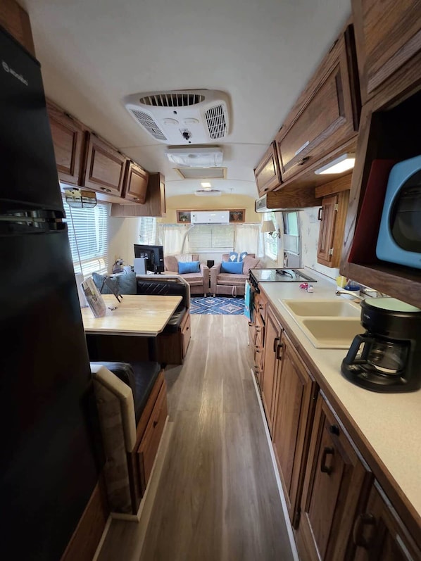 A compact RV interior with a kitchenette, a dining area, and a seating space.