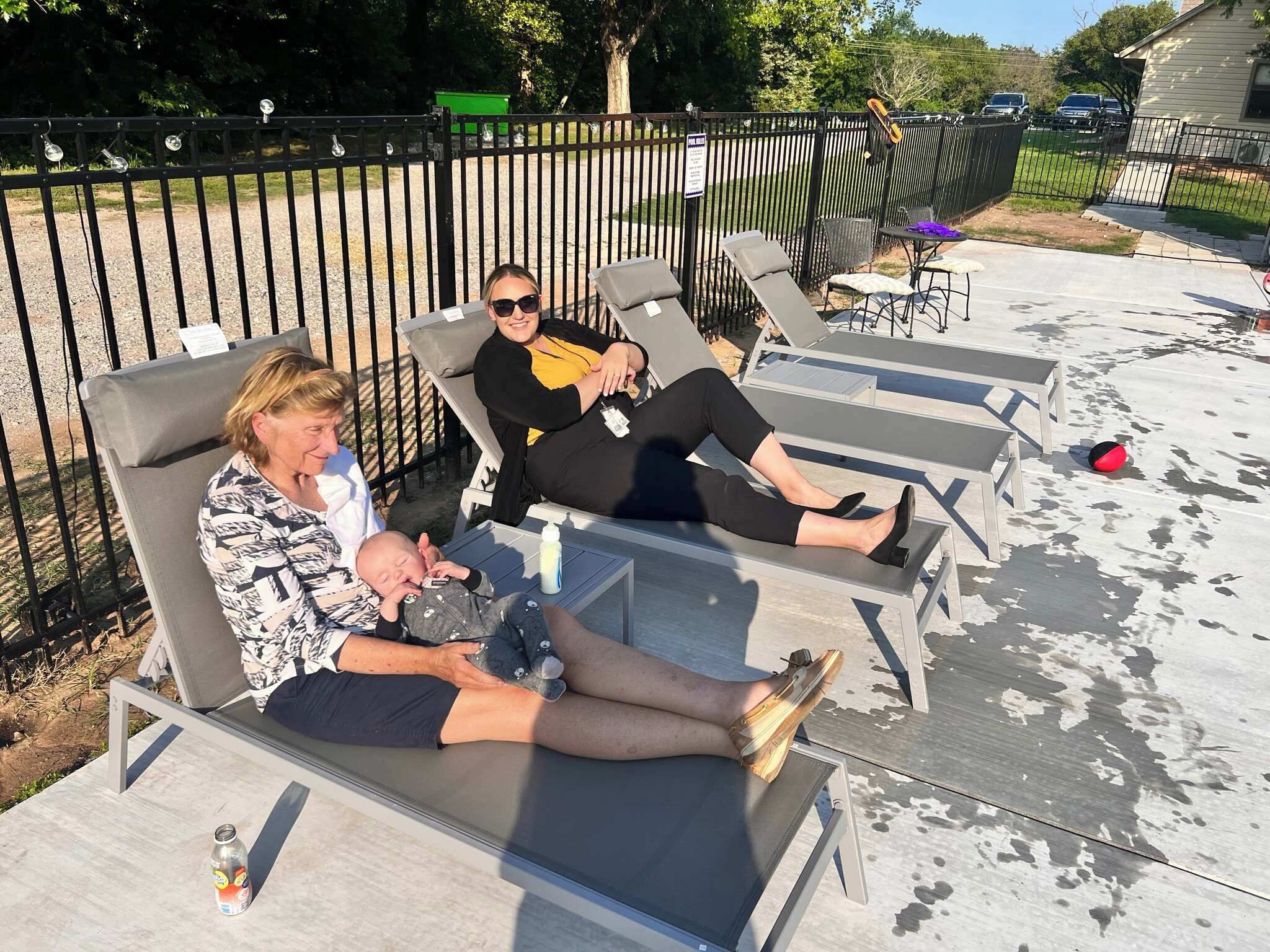 A patio with sun loungers, a baby, and a person holding a baby.