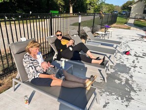Une terrasse avec des chaises longues, un bébé et une personne tenant un bébé.