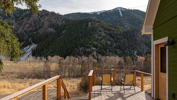 A wooden deck with two chairs and a view of a forested mountain.