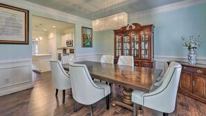 A dining area with a wooden table, white upholstered chairs, a chandelier, and a wooden cabinet with glass doors. - Jackson Getaway + Yard, 4 Mi to High Falls SP (Jackson)