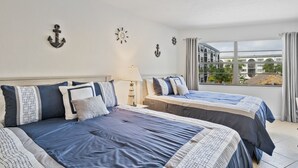 A hotel room with two beds, nautical decor, a large window with a view, and a balcony. - NEW LISTING!  Adorable condo, everything is new! Fantastic location! (Marco Island)