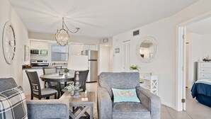 A modern living room with grey sofas, a dining table, and a kitchen in the background. - NEW LISTING!  Adorable condo, everything is new! Fantastic location! (Marco Island)