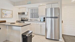 A modern kitchen with white cabinets, stainless steel appliances, and a central island. - NEW LISTING!  Adorable condo, everything is new! Fantastic location! (Marco Island)