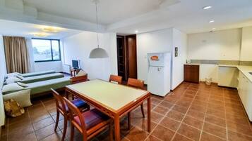 A compact living space with a dining area, kitchenette, and a sofa with a view.