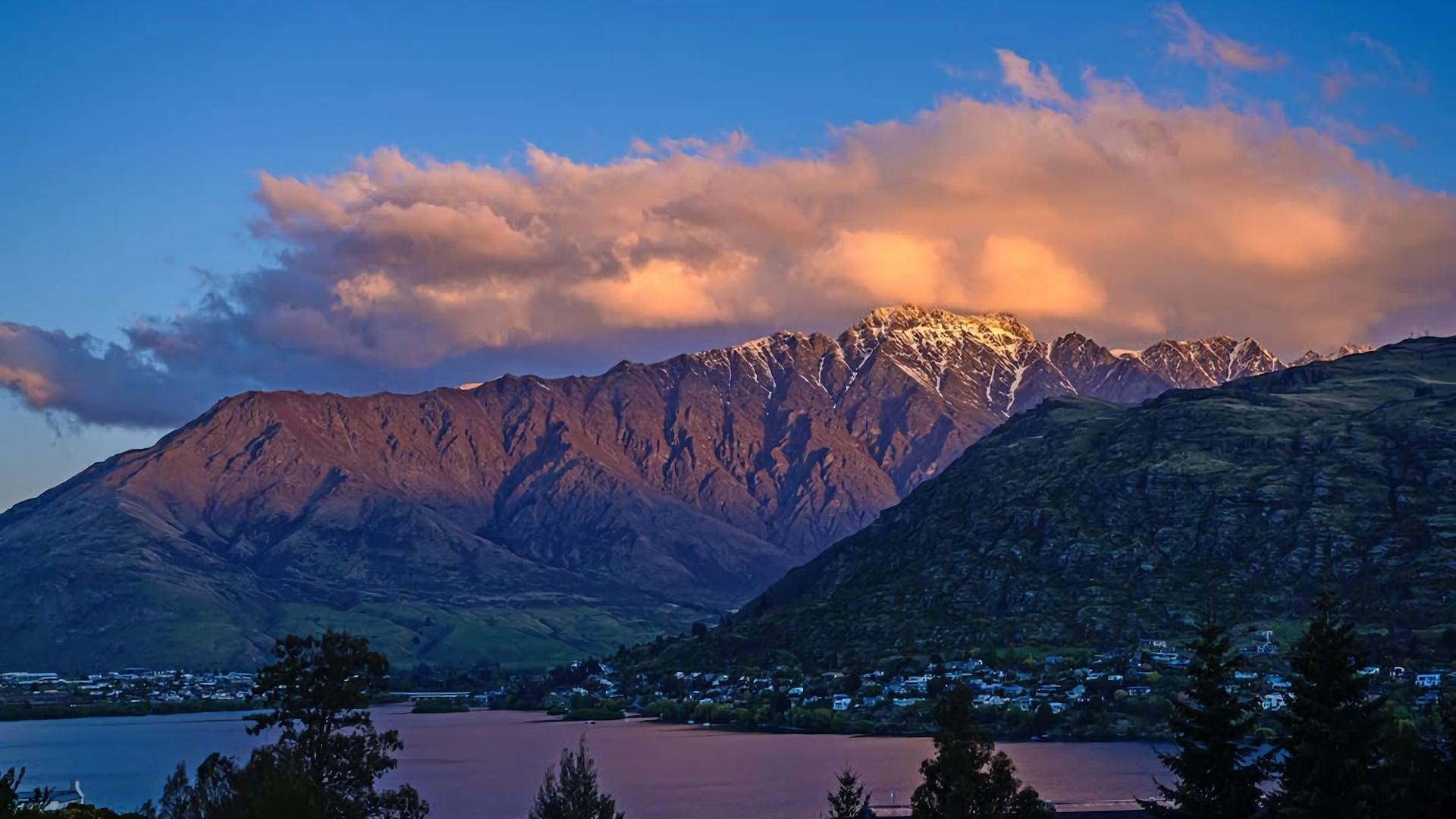 A mountain range with a lake in the foreground and a town below.