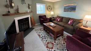 A living room with a fireplace, a sofa, a coffee table, and a TV.