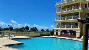 A swimming pool adjacent to a multi-story building with balconies. - Oceanfront Penthouse Overlooking the Atlantic Ocean (Daufuskie Island)