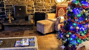 A cozy living room with a stone fireplace, a Christmas tree, and a comfortable seating area. - Butterfly Lodge, historic converted cart house with rural country views (Wearhead)