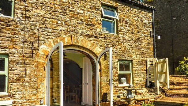 A stone building with a large arched doorway, a small window, and a bench outside. - Butterfly Lodge, historic converted cart house with rural country views (Wearhead)