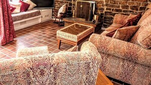 A cozy living room with a stone fireplace, patterned sofas, and a television. - Butterfly Lodge, historic converted cart house with rural country views (Wearhead)
