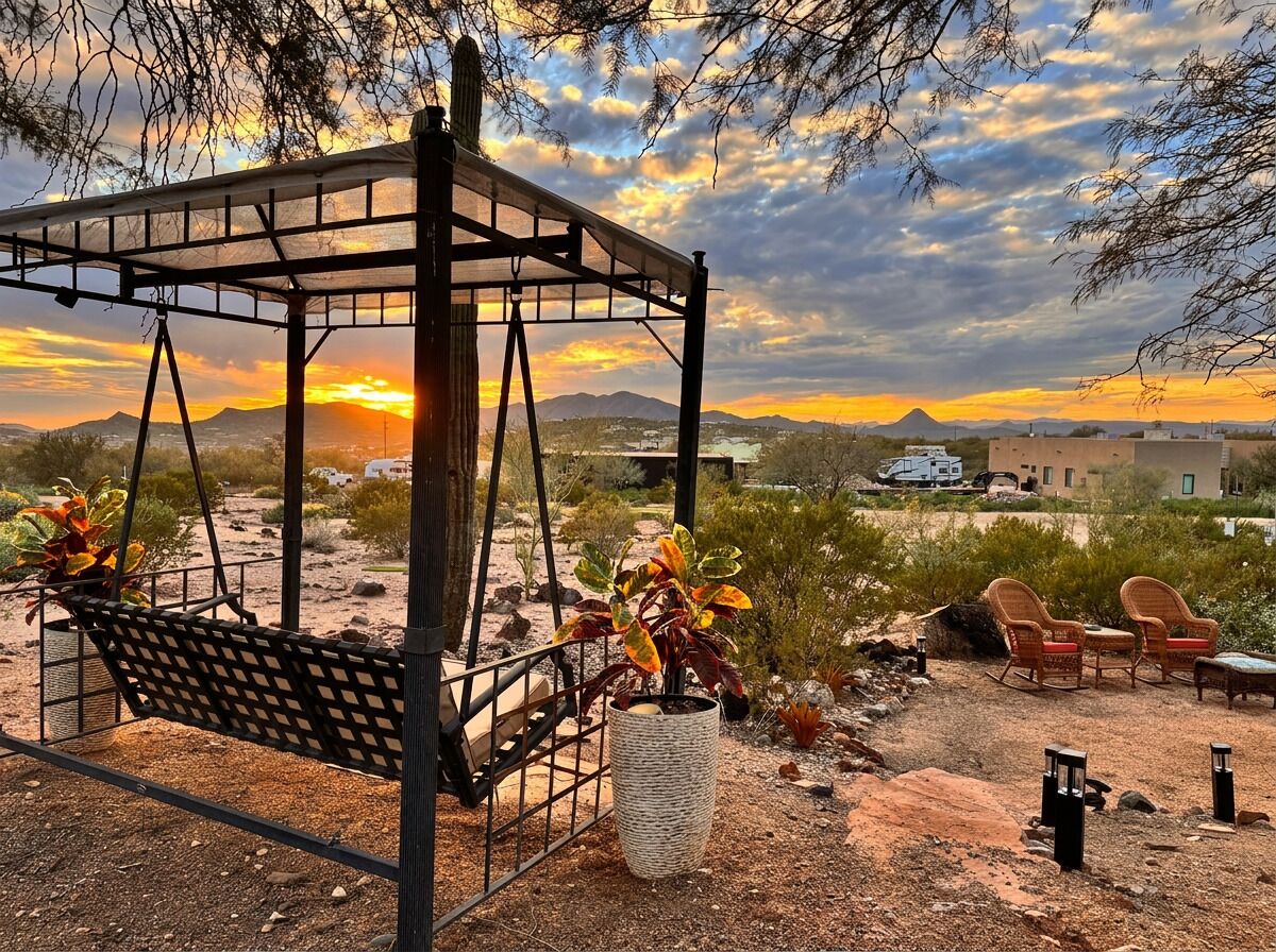 Eine Hängematte unter einer Pergola mit Wüstenpflanzen, Sitzgelegenheiten im Freien und Blick auf einen Sonnenuntergang.