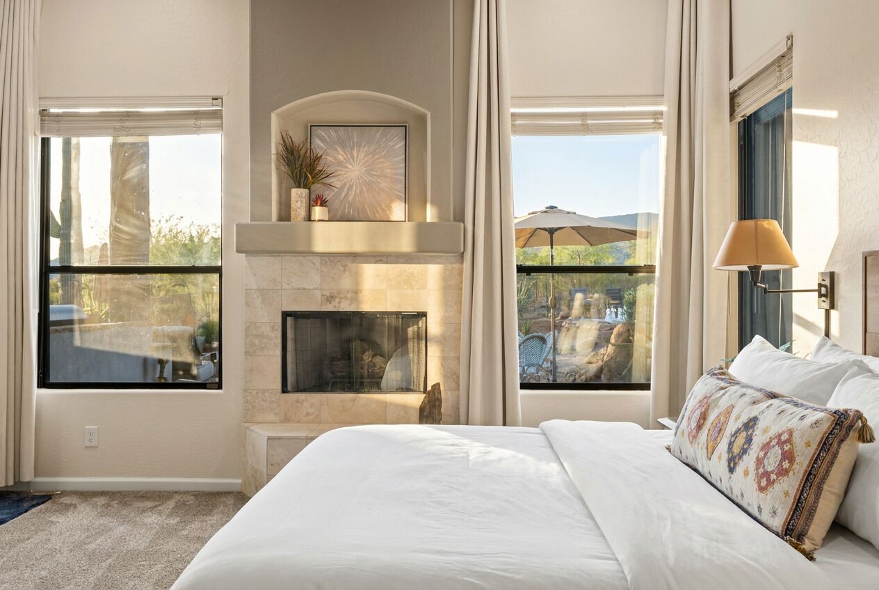 Une chambre d’hôtel avec une cheminée, de grandes fenêtres, un lit et une vue sur l’extérieur.