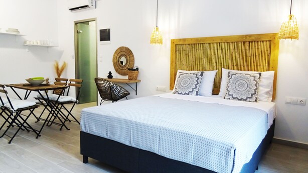 A hotel room with a bed, a dining table, chairs, and a small kitchen area. - Callas Residence (Rhodes)