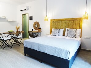 A hotel room with a bed, a dining table, chairs, and a small kitchen area. - Callas Residence (Rhodes)