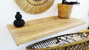 A round woven wall art piece, a black vase, a woven basket with a black object, a woven chair, and a wooden shelf. - Callas Residence (Rhodes)