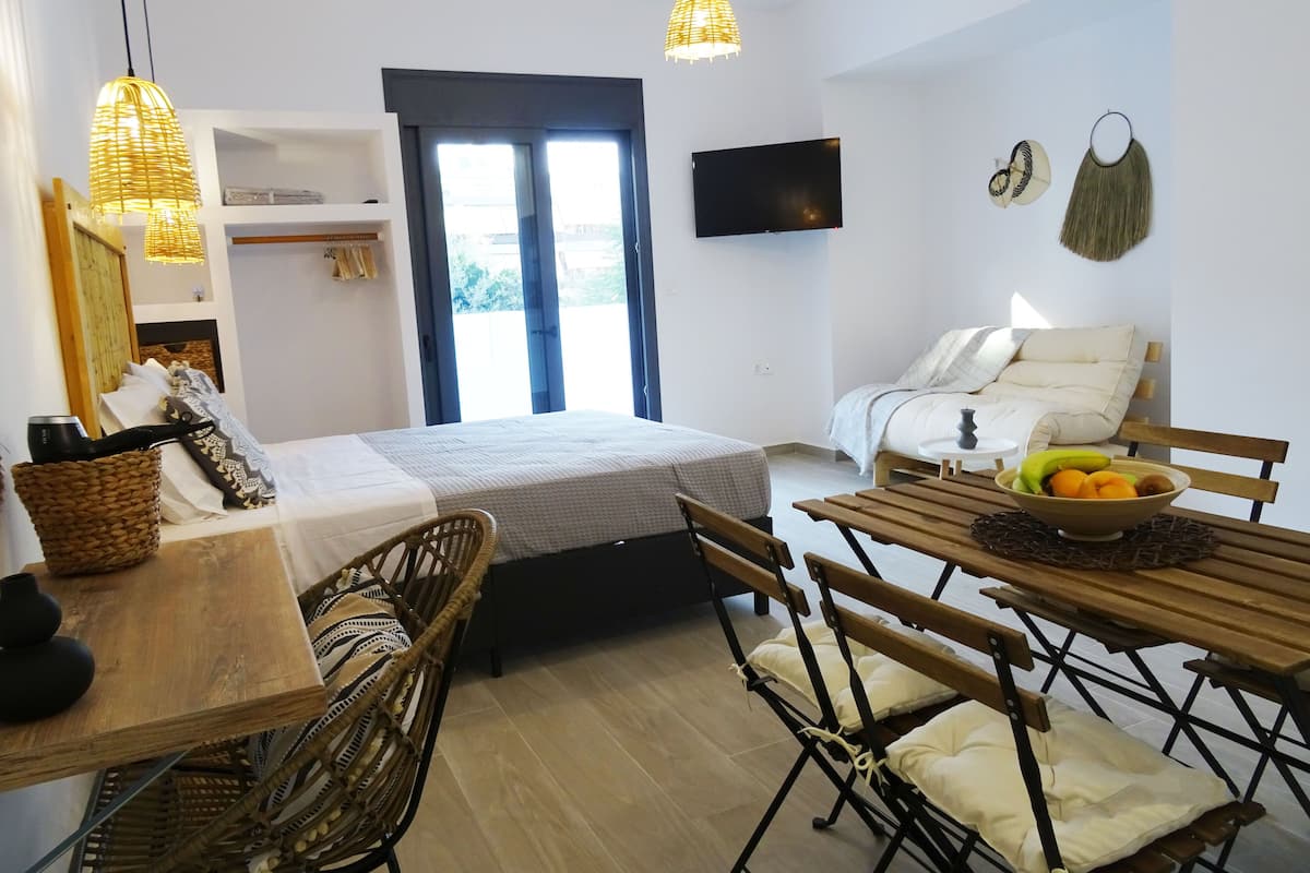 Une pièce comprenant un lit, une table à manger avec des chaises, un téléviseur et une fenêtre avec des rideaux.