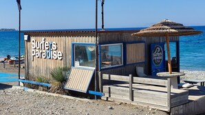 A wooden beach hut with a sign reading "Surfer's Paradise" and a flagpole. - Callas Residence (Rhodes)