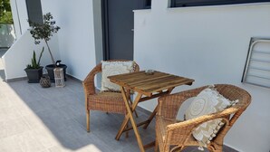 A patio with wicker furniture, a table, and potted plants. - Callas Residence (Rhodes)