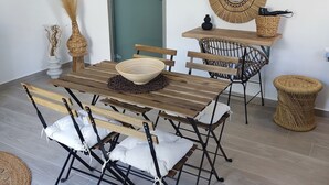 A dining area with a wooden table and chairs, a woven basket, and a wall-mounted mirror. - Callas Residence (Rhodes)